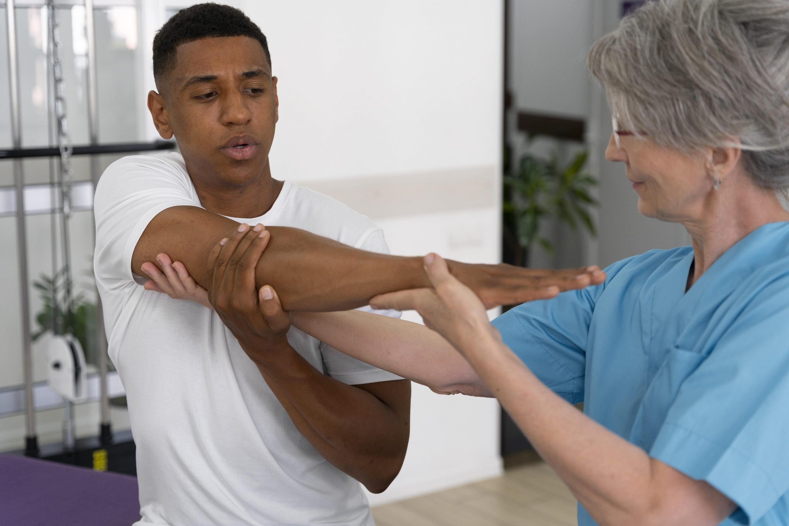 Paciente fazendo fisioterapia para o ombro com ajuda de médica.