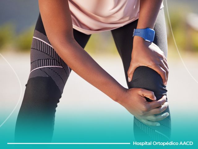 Atleta de corrida segura um dos joelhos com fratura óssea por estresse.