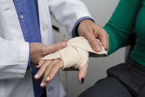 Médica aplicando a bandagem na mão da paciente