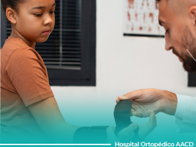 Médico coloca tala removível em criança com punho lesionado nas férias.