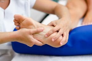 Profissional avaliando a região plantar do pé de uma pessoa durante atendimento.