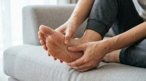 Pessoa massageia a sola do pé enquanto está sentada