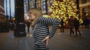 Mulher com dor na região lombar durante atividade cotidiana.